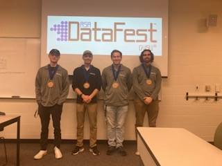 Four students awarded the Best Data Visualization Award pose in front of the DataFest logo.